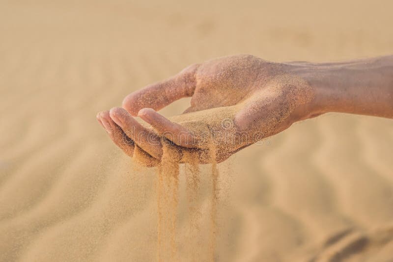 Desert, Sand Puffs through the Fingers of a Man`s Hand Stock Photo