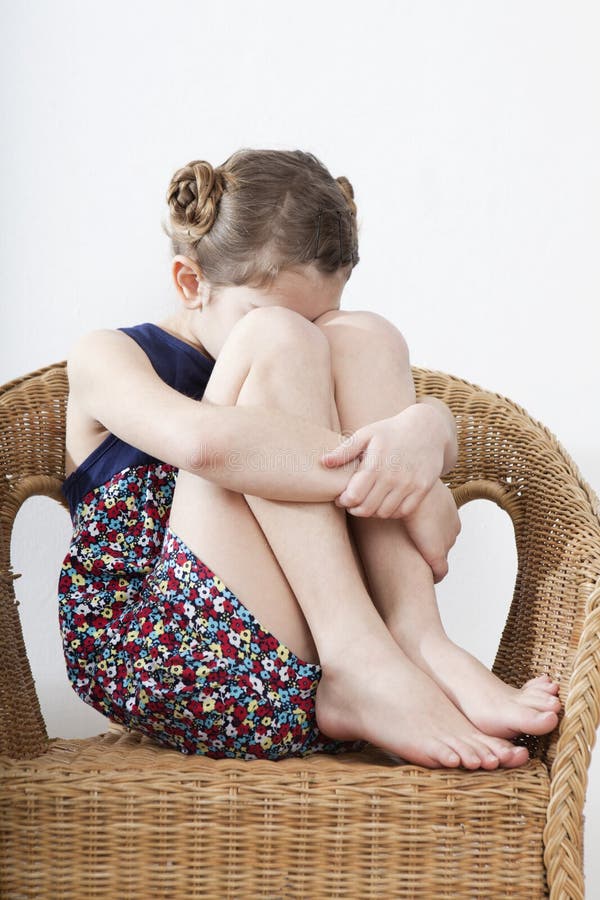 A Criança Indefeso Pequena Huddled No Sofá Foto de Stock - Imagem