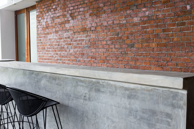 Design of interior, counter bar made from cement with iron seat bar stool and brick wall background