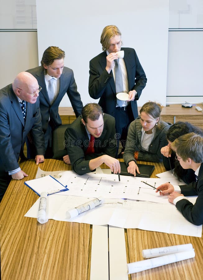 Design Team Meeting. Seven people gathering around the architectural plans, discussing the design in an office cubicle stock photography Design Team Meeting. Seven people gathering around the architectural plans, discussing the design in an office cubicle stock photography