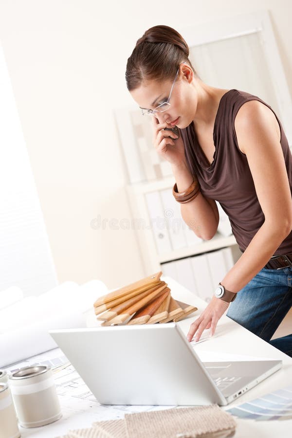 Designer de interior feminin cu laptop și telefon royalty free stock image