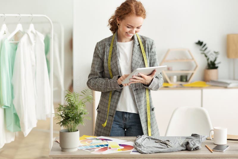 Designer de modă care răsfoiește noua colecție de schițe pe tabletă royalty free stock photos