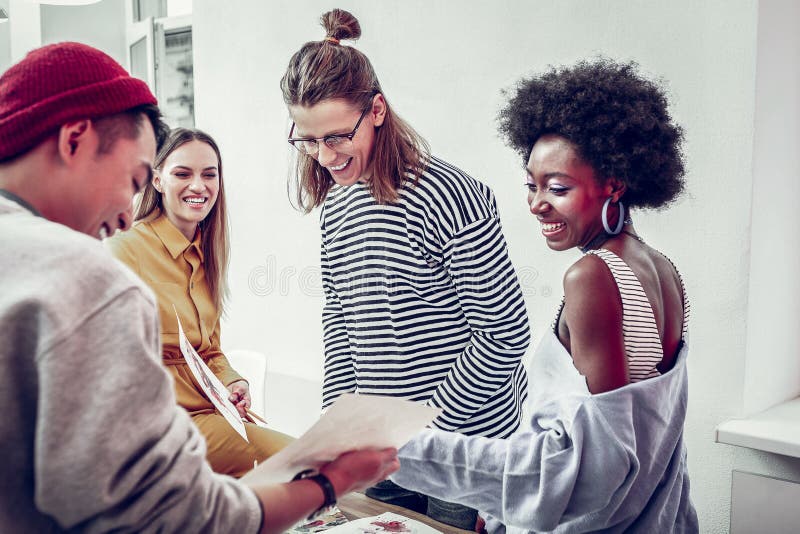 Designeri cu rase mixte și veseli care discută despre o imagine amuzantă stock photo