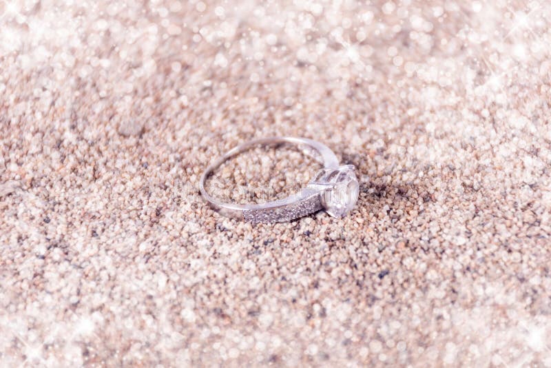 Designersilberhochzeitringe auf Sand und weichem und unscharfem Hintergrund des funkelnden Funkelns stockfotos Designersilberhochzeitringe auf Sand und weichem und unscharfem Hintergrund des funkelnden Funkelns stockfotos