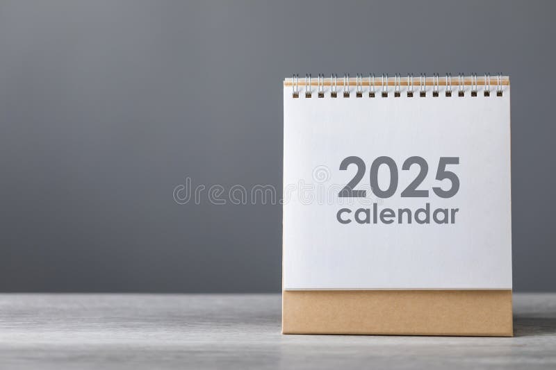 A 2025 desk calendar is placed on a table against a gray background. The simple setup highlights the beginning of the new year royalty free stock photos