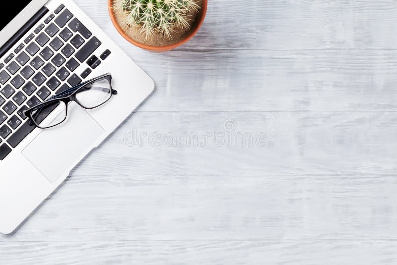 Desk table with laptop, glasses and cactus plant