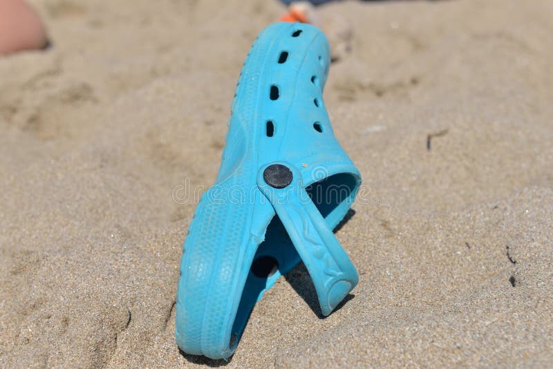 Deslizadores azuis para as crianças esquecidas em um dia ensolarado na praia fotografia de stock Deslizadores azuis para as crianças esquecidas em um dia ensolarado na praia fotografia de stock