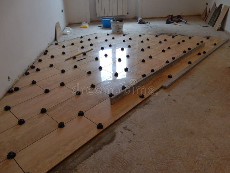 Working phase for the installation of a tile floor with travertine marble effect with appropriate leveling. Working phase for the installation of a tile floor with travertine marble effect with appropriate leveling