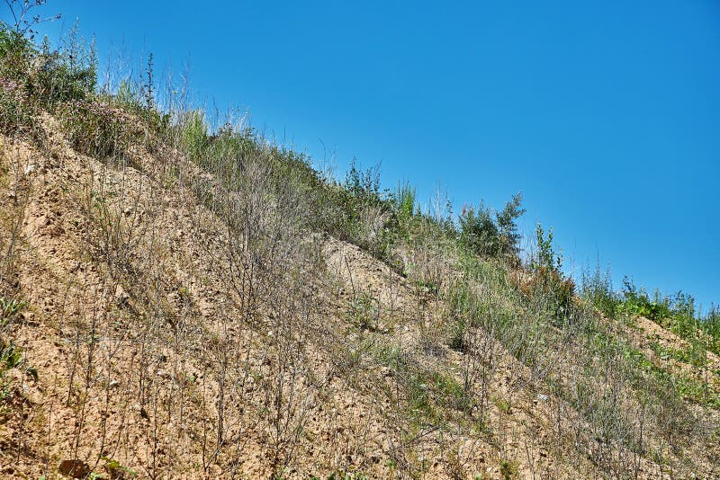 Land with sparse grass in front of a blue sky stock image
