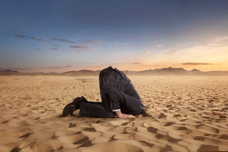 Desparate businessman hiding head in the sand stock image