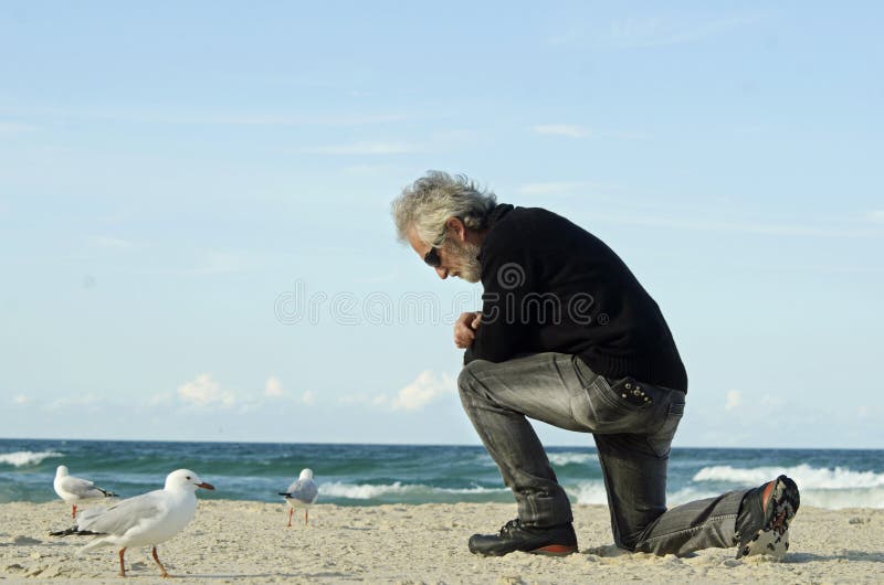 Desperacki smutny osamotniony mężczyzna ono modli się samotnie na ocean plaży