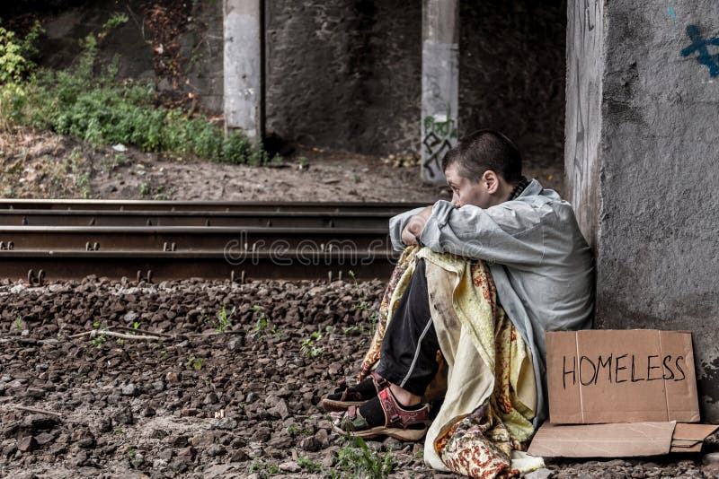 Poor homeless woman with sign sitting on the street near the rail track. Poor homeless woman with sign sitting on the street near the rail track