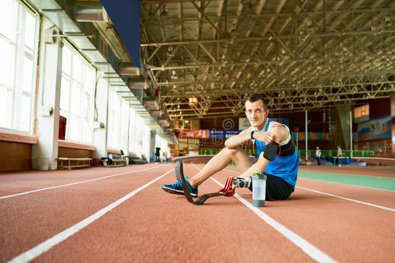 Desportista deficiente que senta-se na pista de atletismo foto de stock royalty free Desportista deficiente que senta-se na pista de atletismo foto de stock royalty free