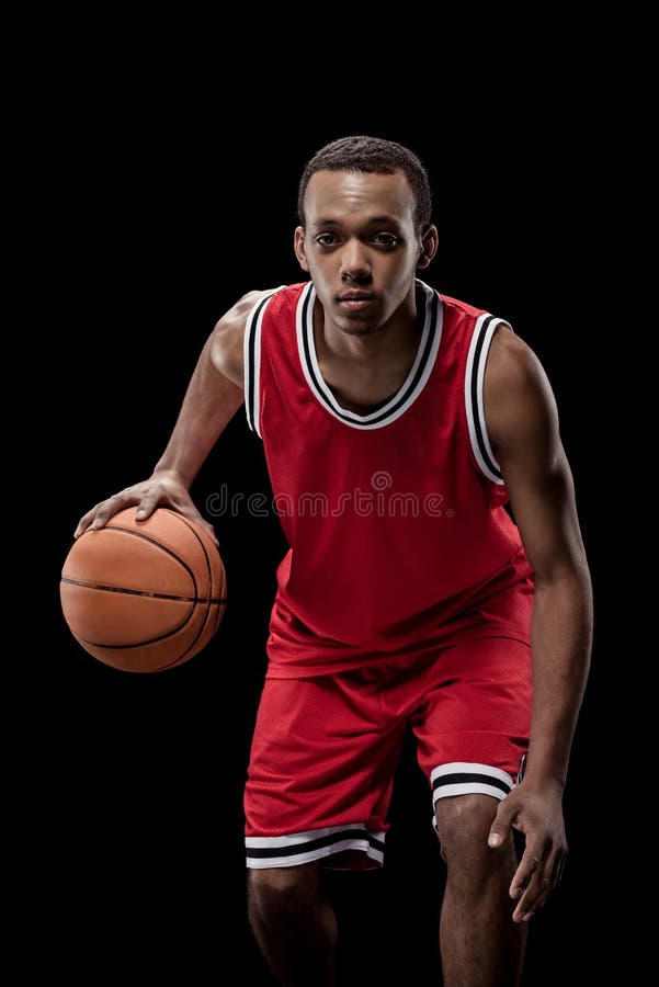 Desportista no uniforme que joga o basquetebol com a bola no preto imagens de stock royalty free Desportista no uniforme que joga o basquetebol com a bola no preto imagens de stock royalty free
