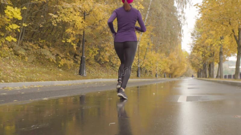 Desportista novo que corre ao longo da estrada