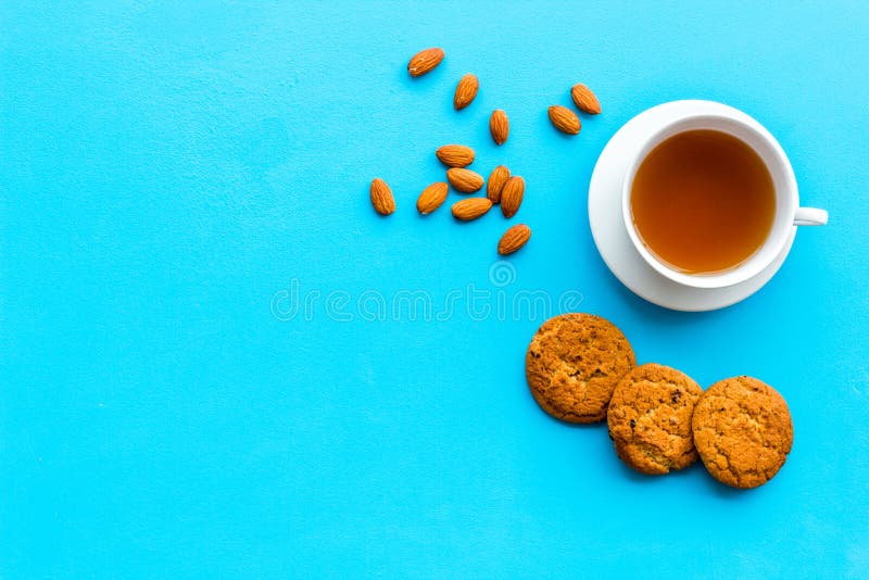 Dessert for evening tea. Cup of tea, fresh homemade cookies on blue background top view copy space