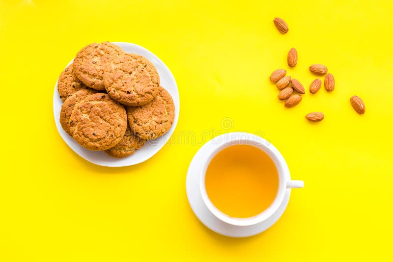 Dessert for evening tea. Cup of tea, fresh homemade cookies on yellow background top view