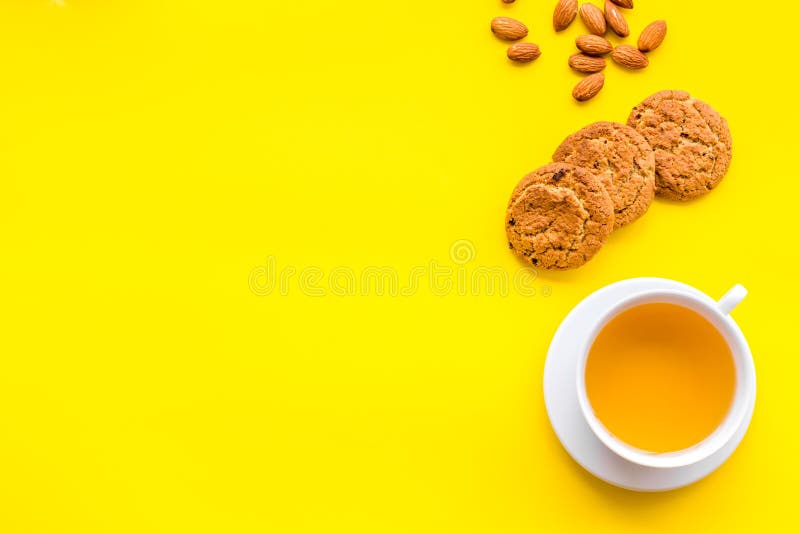 Dessert for evening tea. Cup of tea, fresh homemade cookies on yellow background top view space for text