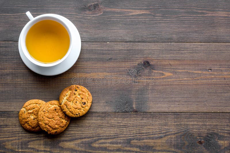 Dessert for evening tea. Cup of tea, fresh homemade cookies on dark wooden background top view copy space