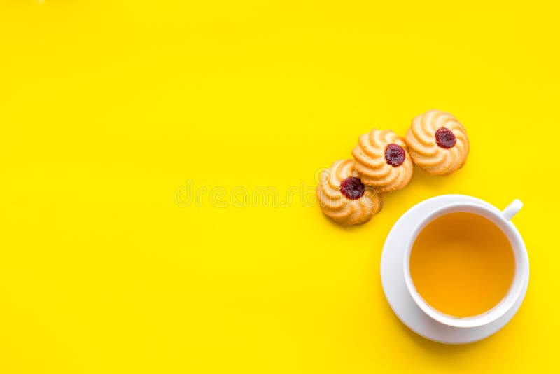 Dessert for evening tea. Cup of tea, fresh homemade cookies on yellow background top view space for text