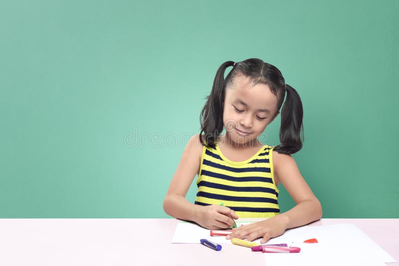 Dessin asiatique mignon de petite fille avec le crayon tout en se reposant au tabl photos libres de droits Dessin asiatique mignon de petite fille avec le crayon tout en se reposant au tabl photos libres de droits