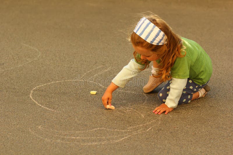 Dessin de fille d'enfant en bas âge avec la craie sur l'asphalte image stock Dessin de fille d'enfant en bas âge avec la craie sur l'asphalte image stock