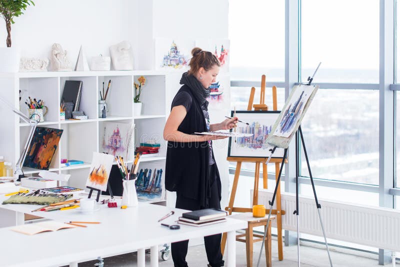 Dessin femelle de peintre dans le studio d'art utilisant le chevalet Portrait d'une peinture de jeune femme avec des peintures d' photo libre de droits Dessin femelle de peintre dans le studio d'art utilisant le chevalet Portrait d'une peinture de jeune femme avec des peintures d' photo libre de droits