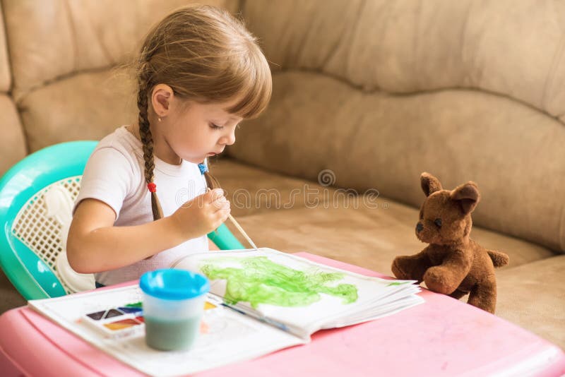 Dessins de coloration de petite fille se reposant à la table, développement de l'enfant images stock Dessins de coloration de petite fille se reposant à la table, développement de l'enfant images stock