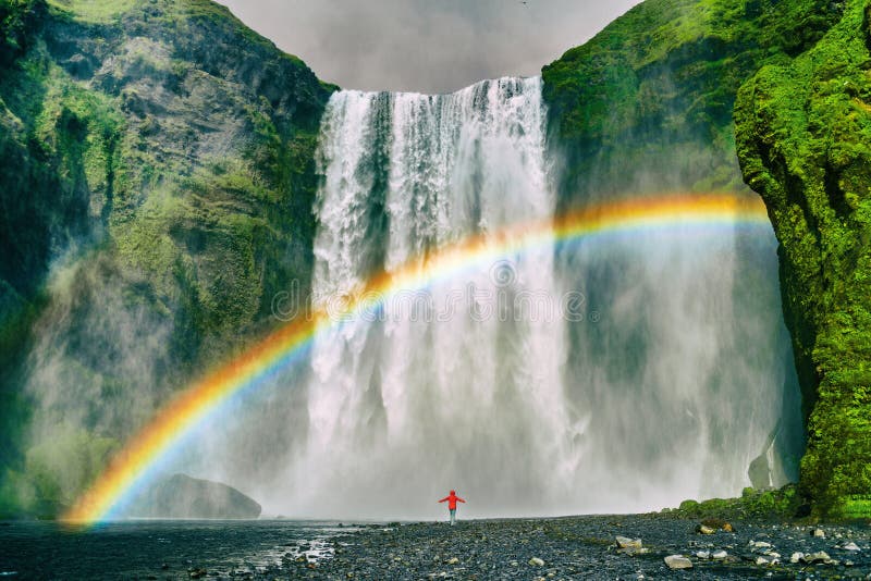 Destination för natur för Island vattenfalllopp berömd turist- Skogafoss vattenfall med regnbågen och kvinnan under vattennedgång royaltyfria bilder Destination för natur för Island vattenfalllopp berömd turist- Skogafoss vattenfall med regnbågen och kvinnan under vattennedgång royaltyfria bilder