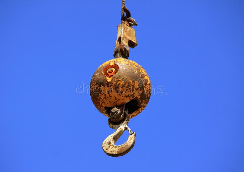 Wrecking ball or demolition ball with hook angainst a blue sky background. Wrecking ball or demolition ball with hook angainst a blue sky background