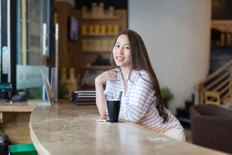 Det asiatiska kafét för sammanträde för kaffe för kvinnadrinkis shoppar arkivfoto Det asiatiska kafét för sammanträde för kaffe för kvinnadrinkis shoppar arkivfoto
