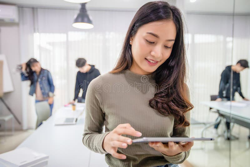 Det asiatiska leendet f?r kvinnastudenter och har roligt och att anv?nda den smarta telefonen och minnestavlan som den hj?lper oc royaltyfri foto Det asiatiska leendet f?r kvinnastudenter och har roligt och att anv?nda den smarta telefonen och minnestavlan som den hj?lper oc royaltyfri foto