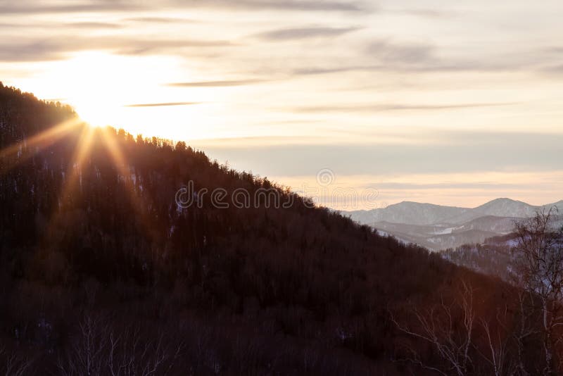 Det bildande landskapet i Altai-bergen med snötäckta toppar under en blå himmel med moln och solsken under vintersolsken arkivbild Det bildande landskapet i Altai-bergen med snötäckta toppar under en blå himmel med moln och solsken under vintersolsken arkivbild