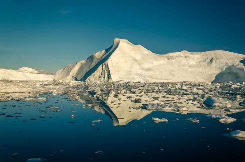 Det enorma isberget i det Ilulissat icefjord- och isfältet reflekterar i vattnet arkivfoto Det enorma isberget i det Ilulissat icefjord- och isfältet reflekterar i vattnet arkivfoto