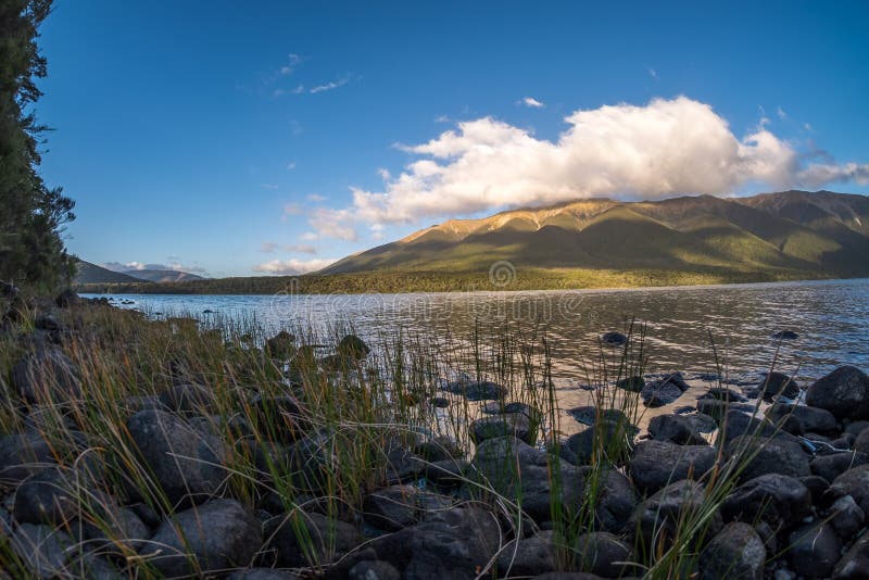 Det fridsamma landskapet av en sjö, fördunklar bildande, kullen och blå himmel royaltyfri fotografi