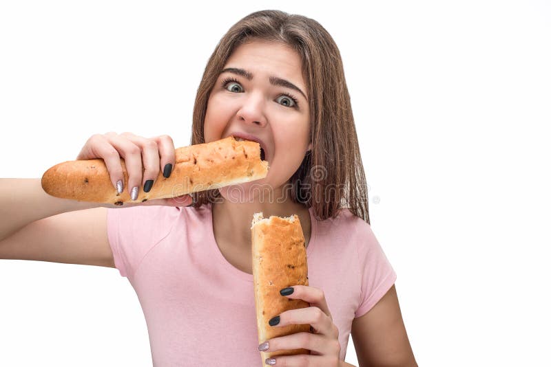 Det hungriga tuggastycket för den unga kvinnan av bagetten rymmer hon båda piees i händer Modellera blicken på kamera Isolerat på royaltyfri bild Det hungriga tuggastycket för den unga kvinnan av bagetten rymmer hon båda piees i händer Modellera blicken på kamera Isolerat på royaltyfri bild