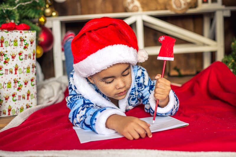 Det härliga afrikanska amerikantsky barnet skrivar ett brev till Santa Claus royaltyfri fotografi Det härliga afrikanska amerikantsky barnet skrivar ett brev till Santa Claus royaltyfri fotografi