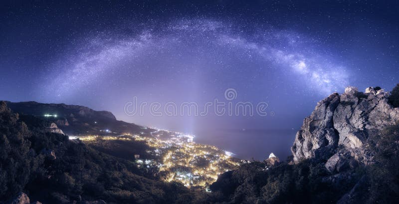 Beautiful night landscape with Milky Way against city lights, mountains, sea and starry sky. Nature background. Beautiful night landscape with Milky Way against city lights, mountains, sea and starry sky. Nature background