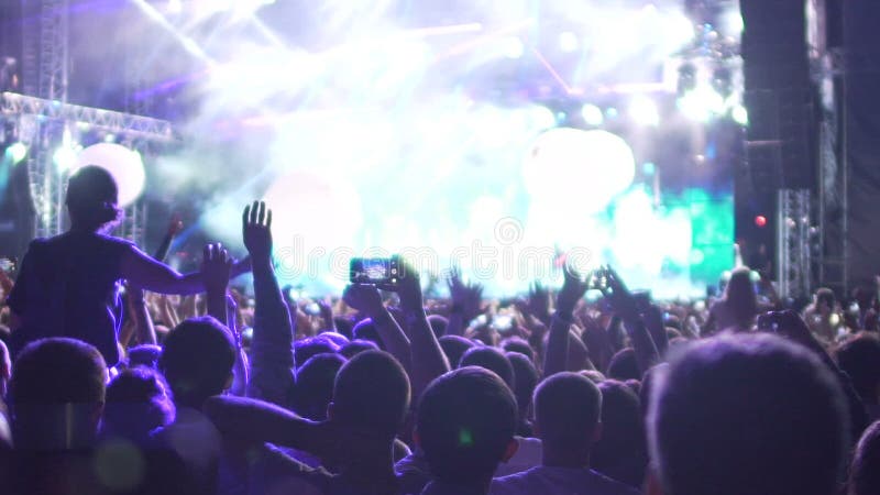 Det lyckliga folket som håller ögonen på fantastisk musik, visar, luftballonger som flyger i konserthall