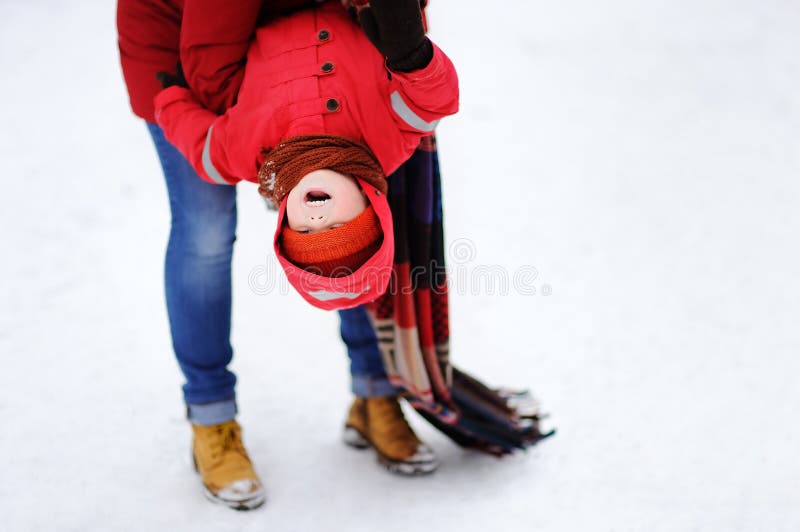 Det roliga lilla barnet och hans moderhavniggyckel i snöig parkerar arkivfoton Det roliga lilla barnet och hans moderhavniggyckel i snöig parkerar arkivfoton