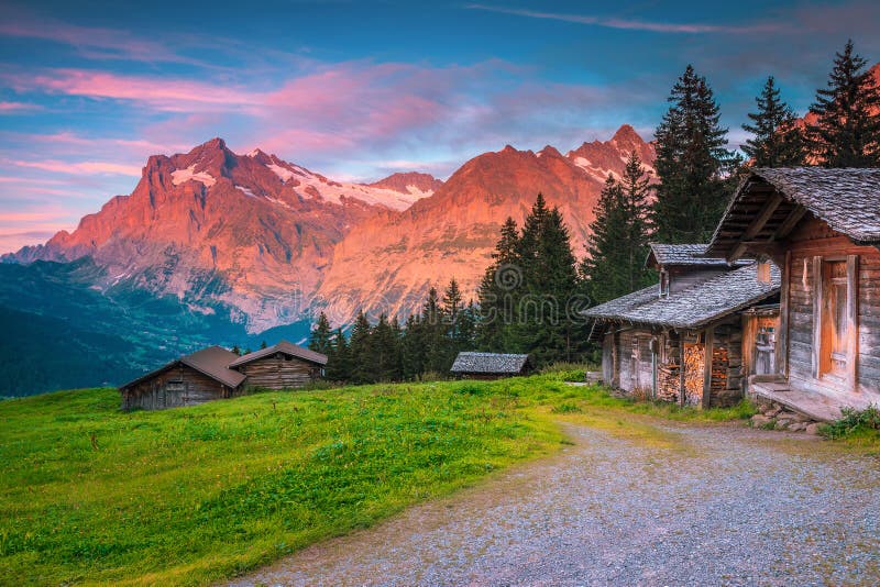 Det underbara alpina läget med träkotter och berg i Schweiz royaltyfria foton Det underbara alpina läget med träkotter och berg i Schweiz royaltyfria foton