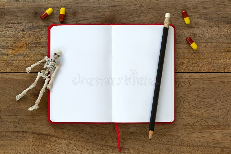 Det vita skelett- liket benar ur att vila på tom vit anteckningsbok w arkivbild