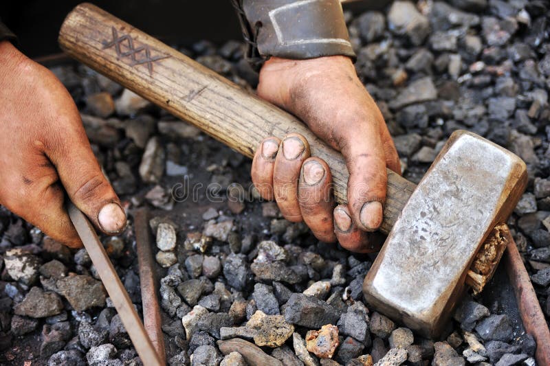 Detail of dirty hands holding hammer and rod