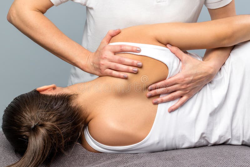 Detail of female therapist manipulating shoulder blade on patient.