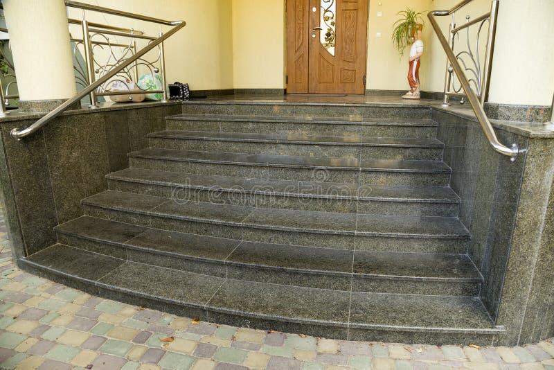 Detail of a house facade. New granite stairs with metal railings