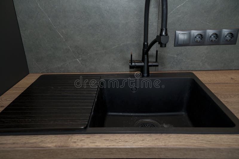 Detail of the interior of a luxury kitchen, a black rectangular sink and a black faucet royalty free stock images