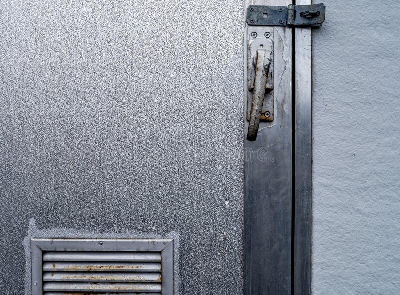 Detail of the latch and vent on a shiny metal utility building stock photography
