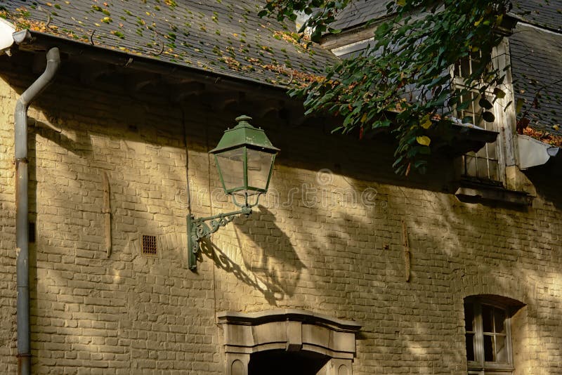 Detail of an old traditional flemish building with lantern, foliage and their shadows royalty free stock photos