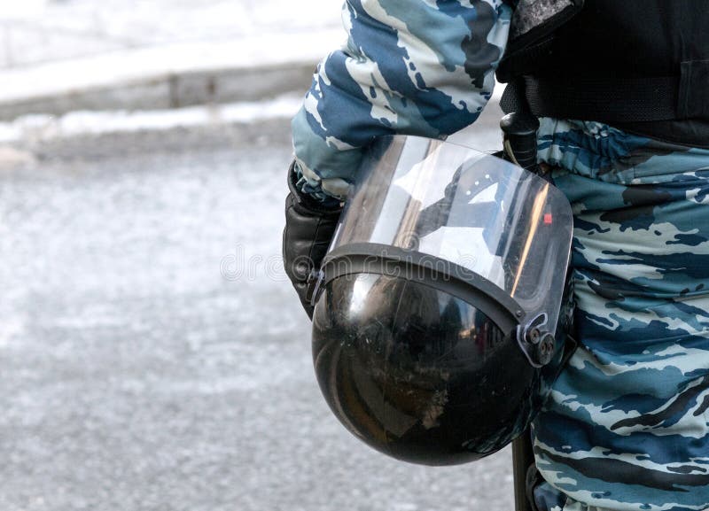 Detail of policeman wearing in camouflage holding protective helmet stock photo