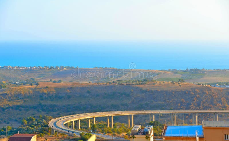 Detail of Ponte Morandi bridge structure with mediterranean sea and coast in background. Agrigento Sicily, Italy.